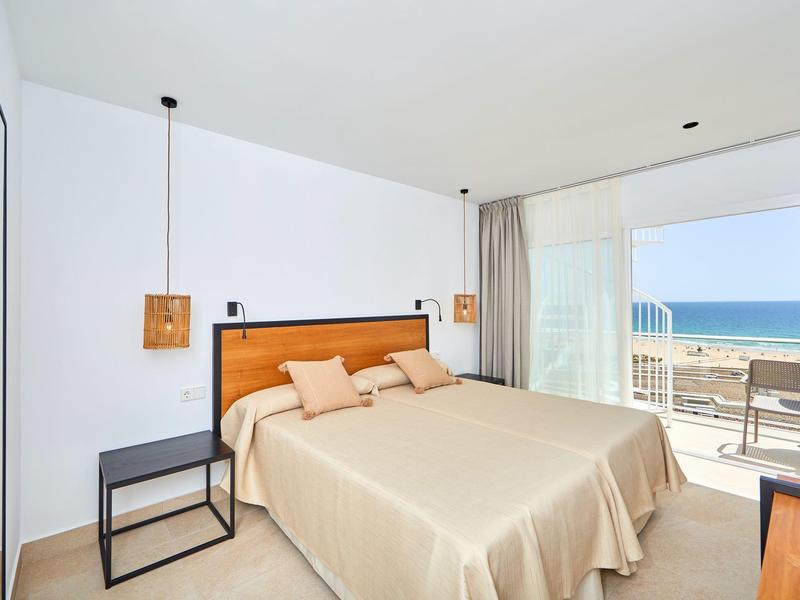 Modernes Hotelzimmer mit Doppelbett, Balkon und Meerblick bei klarem Himmel