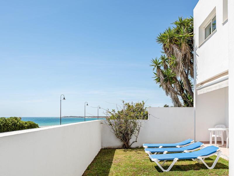 Zwei blaue Liegestühle auf einer Terrasse mit Blick auf das Meer und klaren Himmel.