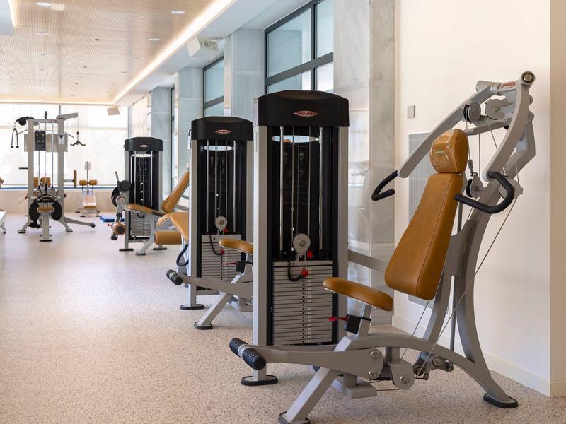 Innenraum eines Fitnessstudios mit modernen Kraftgeräten, weichem Boden und großem Fensterausblick.