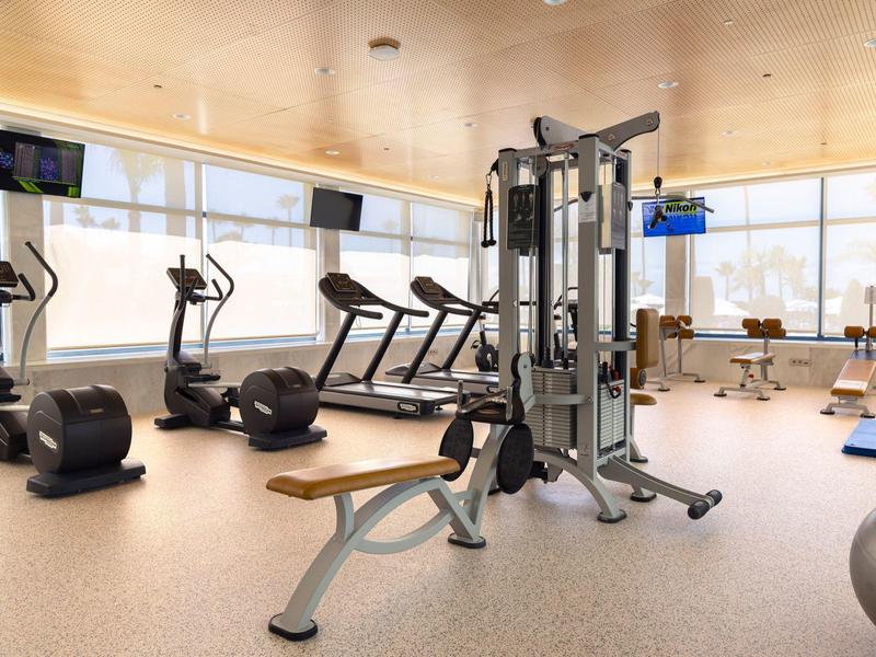 Moderner Fitnessraum mit Laufbändern, Rudergeräten und Kraftgeräten in hellem, offenem Raum.