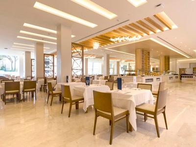 Helles, modernes Restaurant mit weiß gedeckten Tischen und Holzstühlen.