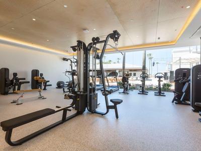 Moderner Fitnessraum mit verschiedenen Trainingsgeräten und großem Fenster für Tageslicht.