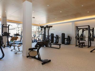 Helles Fitnessstudio mit modernen Geräten und großen Fenstern für Tageslicht.