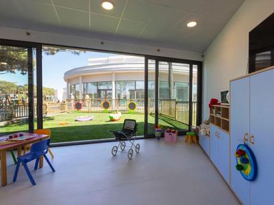 Heller Spielraum mit großen Fenstern, kindgerechten Möbeln und Blick auf einen Garten.