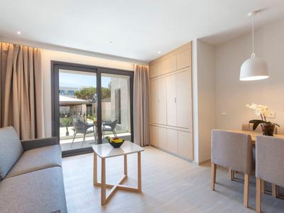 Heller Wohnbereich mit Sofa, Esstisch, eingebauten Schränken und Zugang zur Terrasse.