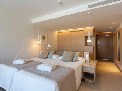 Modernes Hotelzimmer mit Doppelbett, beigen Bettdecken und weichen Kissen, minimalistischem Design.