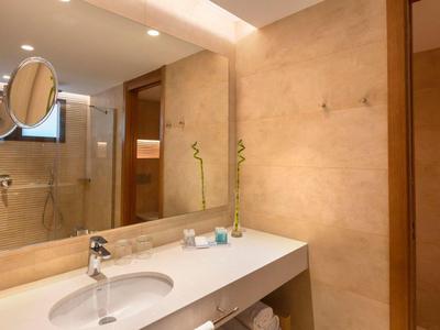 Moderner Badezimmer-Waschtisch mit großem Spiegel und Dusche im Hintergrund