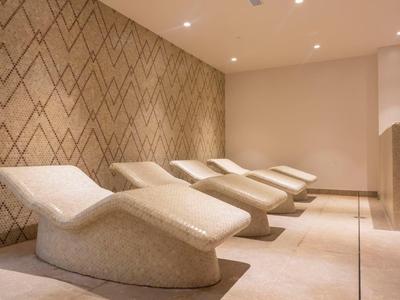 Moderne Liegen in einem ruhigen, minimalistisch gestalteten Wellnessbereich mit warmen Farben.