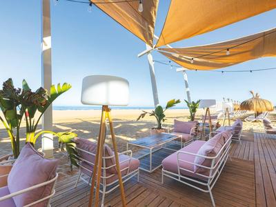 Moderner Außenbereich mit gemütlichen Sitzgelegenheiten und Sonnensegeln mit Meerblick.