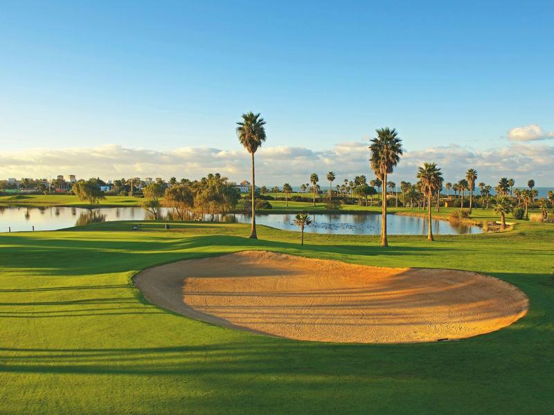 Moderner heller Barbereich mit weißen Barhockern, Holzdetails und hexagonalen Deckenlampen.