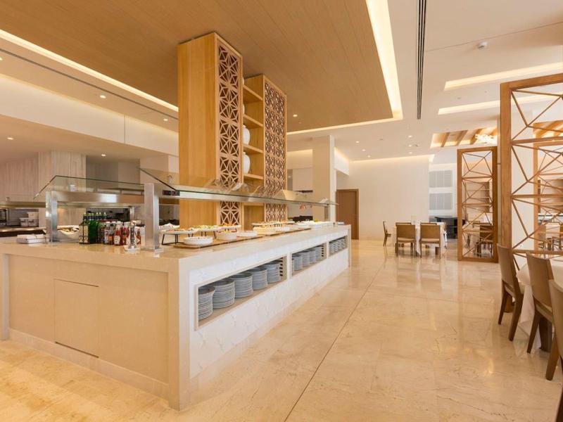 Helles Buffet und Essbereich mit Holzmöbeln in einem modernen Hotelrestaurant.