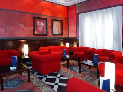 Innenraum eines roten Wohnzimmers mit bequemen Sofas, Teppichen und beleuchteten Lampen.