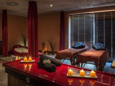 Ruheraum mit Massageliegen, Kerzen, warmem Licht und entspannter Atmosphäre.