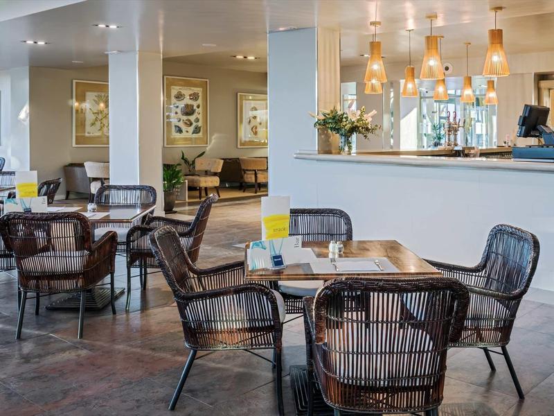 Modernes Café mit Korbsesseln, runden Tischen und hellem, einladendem Ambiente.