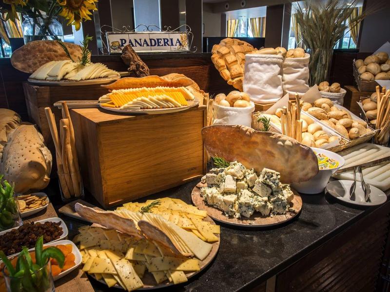 Verschiedene Brotsorten und Gebäck stehen auf einem dunklen Buffet mit rustikalem Holzdekor.