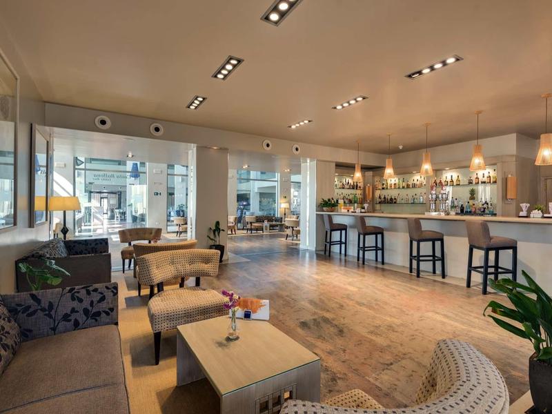 Helles, modernes Café mit Holzfußboden, gemütlichen Sitzgruppen und langer Bar mit Barhockern.