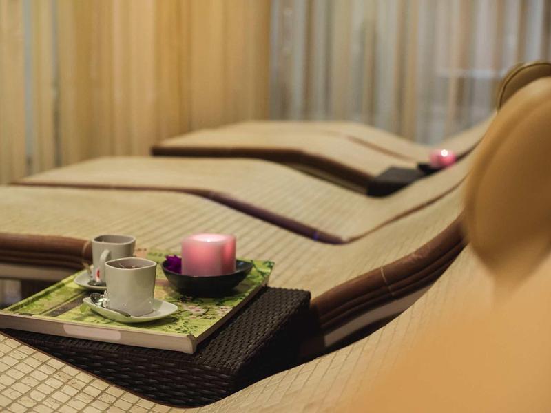 Entspannungsbereich mit Liegen, braun-beiger Polsterung und Serviertablett mit Kerze und Tasse.