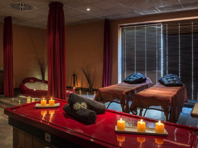 Ruheraum mit Massageliegen, Kerzen, warmem Licht und entspannter Atmosphäre.