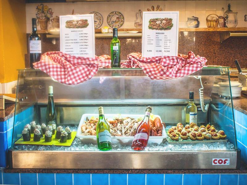 Theke mit Snacks, Flaschen und Speisekarten, umgeben von blau gekachelten Wänden.