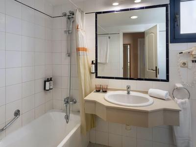 Modernes Hotelbadezimmer mit Badewanne, Waschbecken, großem Spiegel und weißen Fliesen.