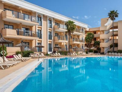 Moderner Hotelpool mit blauen Wasser, umgeben von Liegestühlen und Palmen an einem sonnigen Tag.