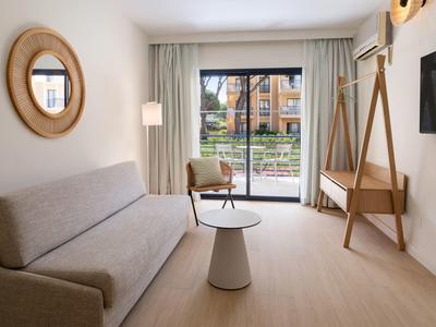 Modern eingerichtetes Wohnzimmer mit Sofa, Sessel, runden Tisch und großer Terrassentür.