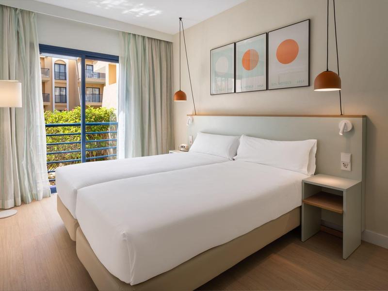 Modernes Hotelzimmer mit zwei Einzelbetten, großem Fenster und minimalistischer Dekoration.