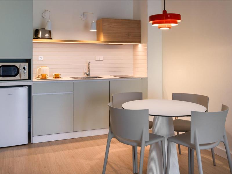 Moderne Küchenzeile mit runden Tisch und vier Stühlen in hellem Zimmer.