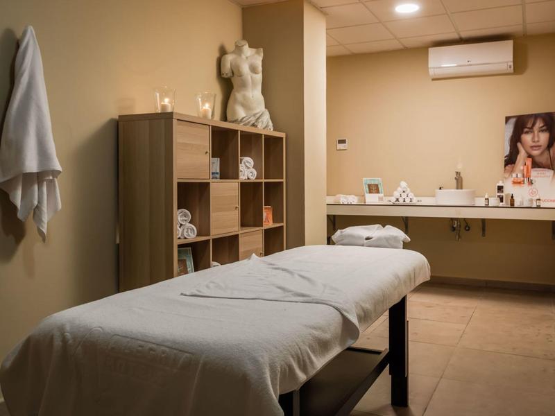 Hellbehandlungsraum mit Massagetisch, Holzmöbeln und beruhigender, warmer Wandfarbe.