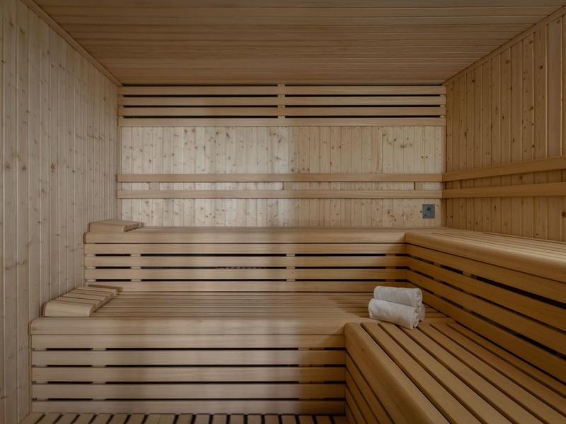 Innenraum einer Sauna mit hellen Holzpanelen, mehrstufigen Sitzbänken und einem weißen Handtuch.