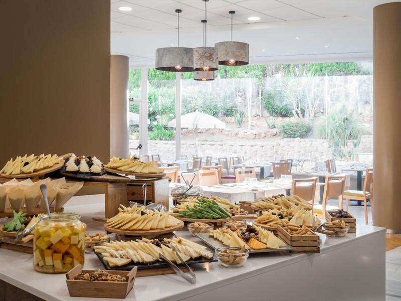 Buffet mit verschiedenen Brotsorten und Snacks in hellem, modernem Restaurant mit großen Fenstern.