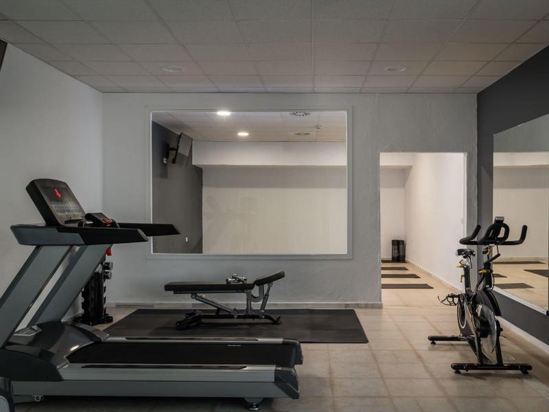 Moderner Fitnessraum mit zwei Laufbändern, Fahrradergometer und großer Wandspiegel.