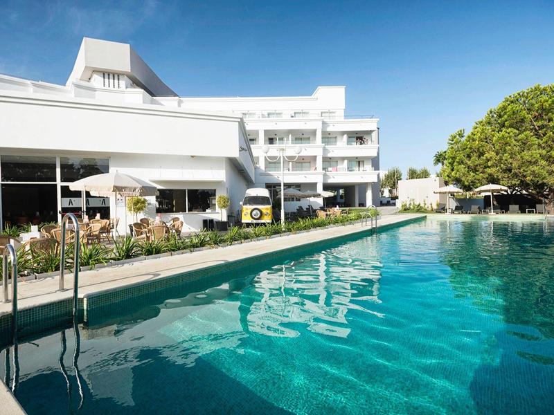 Kinderpool mit Krake-Skulptur, rutschiger Wasserbahn und sprudelnden Fontänen in hellem Sonnenlicht.