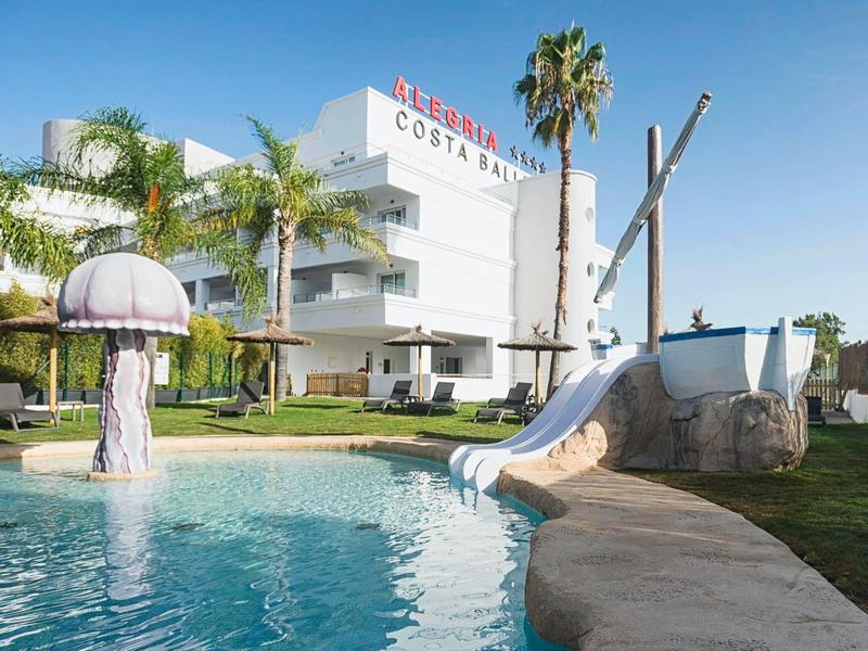 Hotel mit Pool, Rutsche, Palmen und großer Quallen-Dekoration an klarem Himmel.