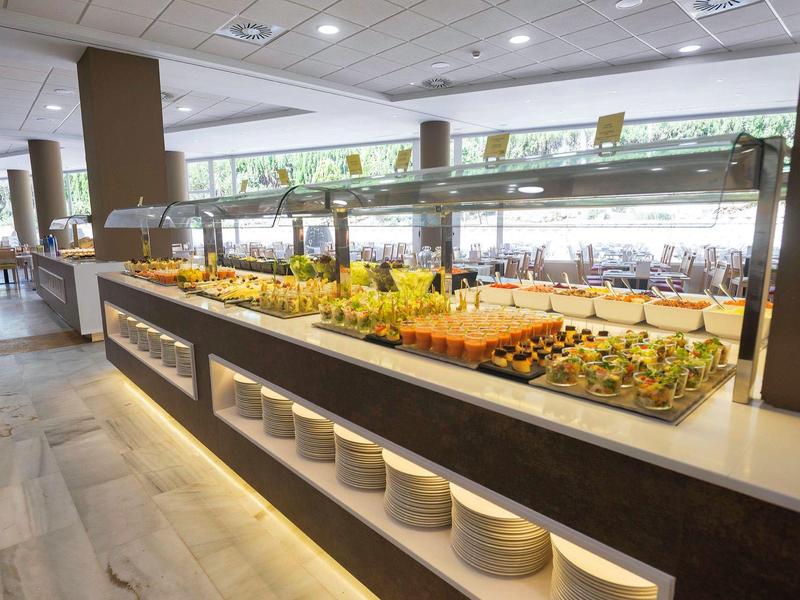 Buffet mit vielfältigem kaltem Essen auf hell beleuchtetem Tresen in modernem Speisesaal.