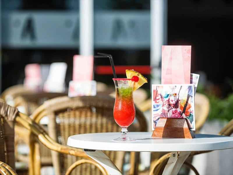 Großer, runder Pool mit blauer Wasserfläche umgeben von Liegestühlen und Sonnenschirmen.