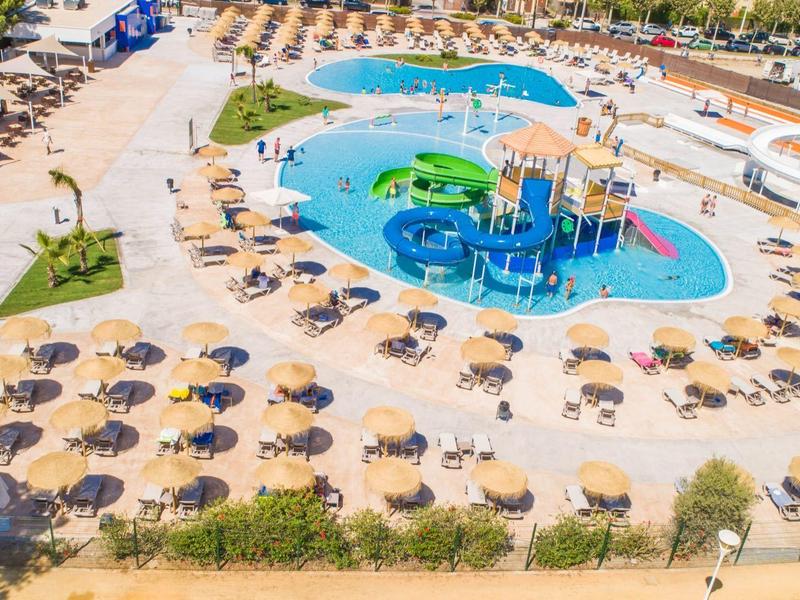 Wasserpark mit Pools, Wasserspielen, Rutschen und vielen Sonnenschirmen in einer großen Freizeitanlage.