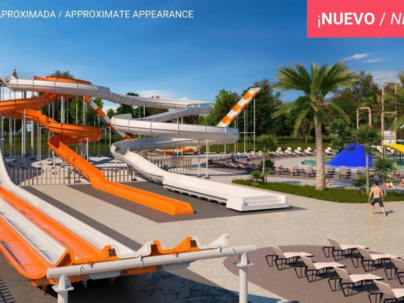 Wasserpark mit großen Rutschen, Pool, Sonnenschirmen und Liegestühlen unter blauem Himmel.