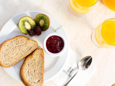 Ein gedeckter Frühstückstisch mit Brot, Kiwi, Marmelade und Orangensaft.