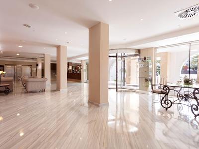 Heller, geräumiger Hotellobby mit Marmorboden und Sitzbereich neben großen Fenstern.