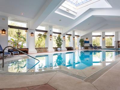 Innenpool mit Liegestühlen, großen Fenstern und Oberlicht, helle, moderne Gestaltung.