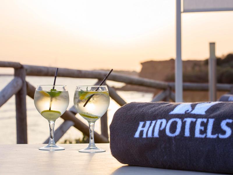 Zwei erfrischende Cocktails mit Minze auf einem Tisch am Meer, daneben ein Handtuch mit Logo.