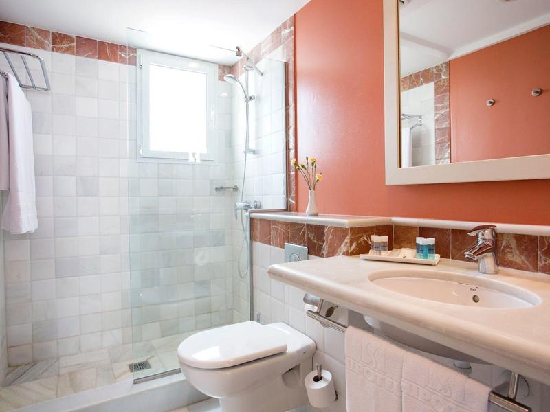 Modernes Badezimmer mit weißer Dusche, Waschbecken, Toilette und orangefarbenen Wänden.