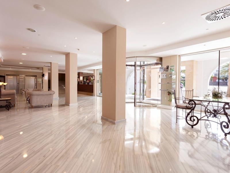 Großer, heller Empfangsbereich mit Marmorboden, Säulen und Glas-Eingangstür.