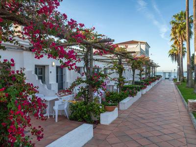 Un paseo con plantas florecientes junto a edificios blancos en un hotel con vista al mar.
