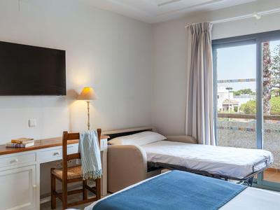 Jasny pokój hotelowy z dwoma łóżkami, biurkiem i dużym oknem z widokiem na zewnątrz.