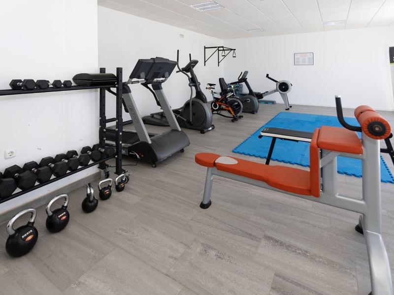 Palestra con tapis roulant, pesi liberi e panca per esercizi.