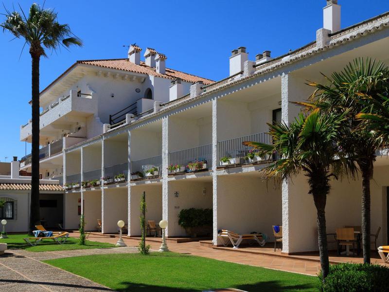 Hotel con balconi e palme sotto un cielo azzurro.