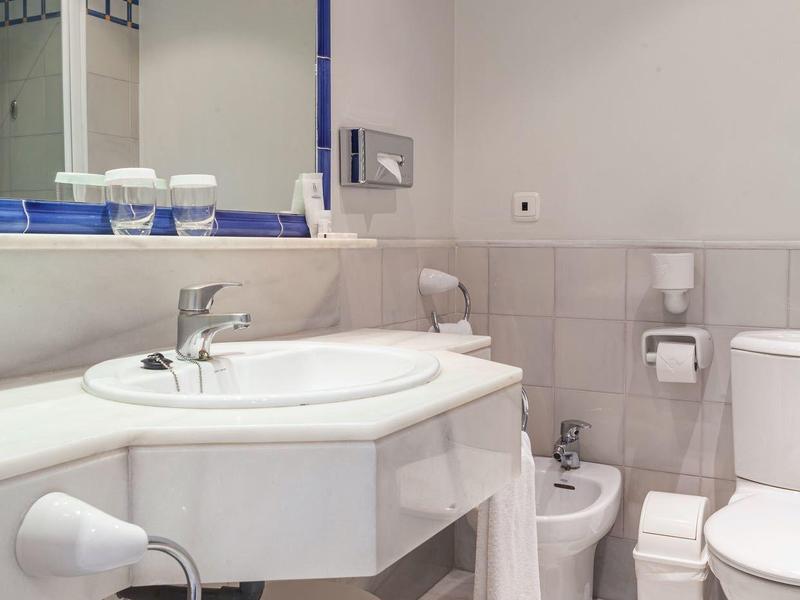 Bagno d'hotel elegante con lavabo, specchio, gabinetto e bidet bianchi.