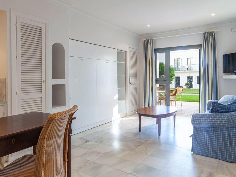 Soggiorno luminoso con divano, tavolino e vista sul giardino attraverso una porta finestra.